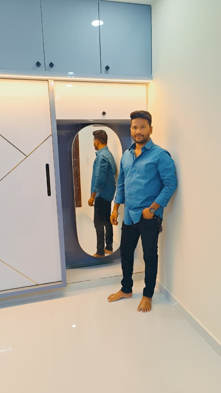 Manohar standing beside a textured interior wall